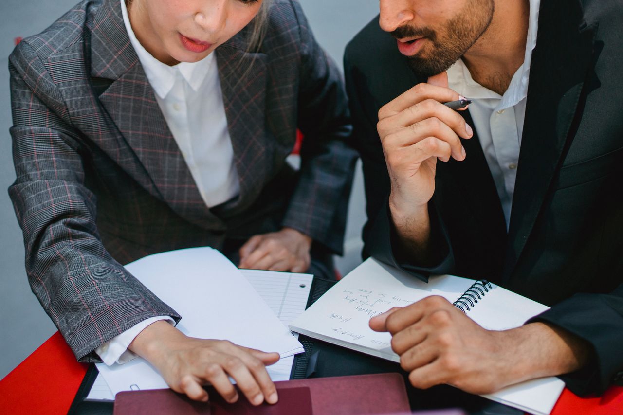 Crafting Captivating Headlines: Your awesome post title goes here Two business professionals discussing plans with notebooks and papers at a meeting.